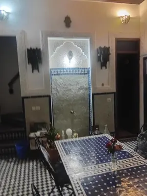 a room with a table and a blue and white tile floor at Riadnomadfes in Fès