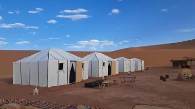 a row of white tents in the desert at Dar chez ali in Mhamid