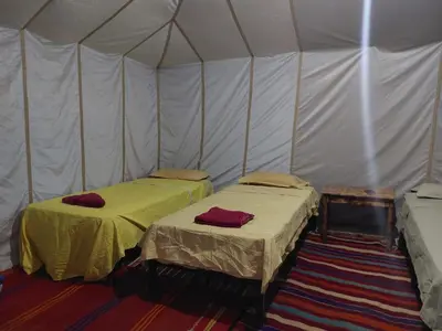 a tent with two beds in a room at Dar chez ali in Mhamid