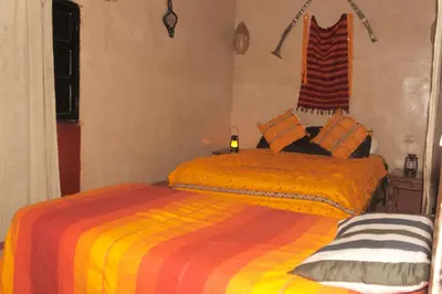 a bedroom with two beds with orange and yellow sheets at Dar dmana chez l'habitant in Skoura