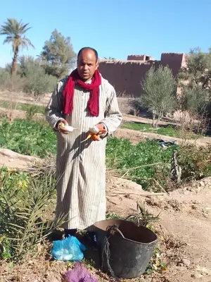 a man standing next to a bucket in a field at Dar dmana chez l'habitant in Skoura