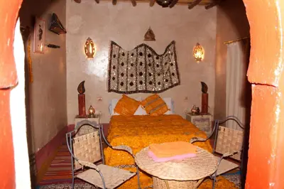 a bedroom with a bed and a table and chairs at Dar dmana chez l'habitant in Skoura