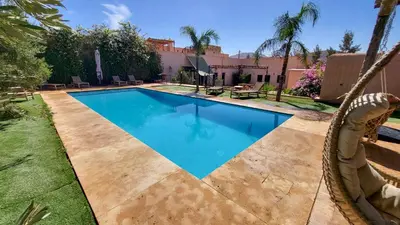a swimming pool with a swing in a yard at Tawenza Lodge in Aït Ourir