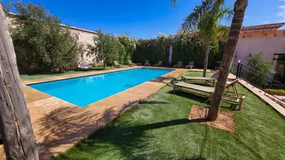 a swimming pool with a bench next to a house at Tawenza Lodge in Aït Ourir