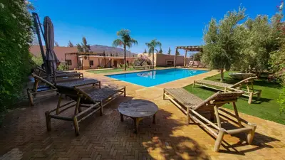 a group of benches sitting next to a pool at Tawenza Lodge in Aït Ourir