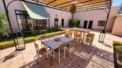 an outdoor patio with tables and chairs and a building at Tawenza Lodge in Aït Ourir