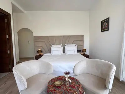 a bedroom with a bed with two chairs and a table at Villa Fiori Luxury Italian Villa, Pool & Spa, Marrakech in Douar bel Rhanodour