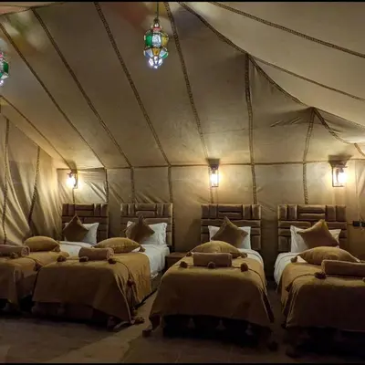 a room with three beds in a tent at Nomad Spirit Camp in Merzouga