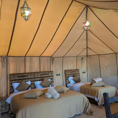a bedroom with two beds in a tent at Nomad Spirit Camp in Merzouga