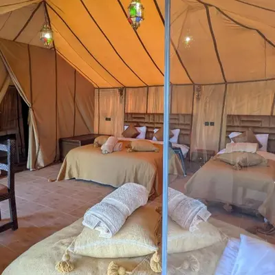 a bedroom with two beds in a tent at Nomad Spirit Camp in Merzouga