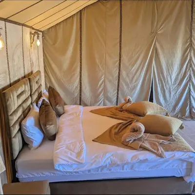 a bed in a tent with pillows on it at Nomad Spirit Camp in Merzouga