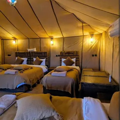 a room with four beds in a tent at Nomad Spirit Camp in Merzouga
