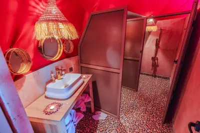 a red bathroom with a sink and a shower at Merzouga Desert Dome camp Erg Chebbi in Merzouga