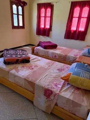 three beds in a room with red windows at Auberge Ighounba in Tinerhir