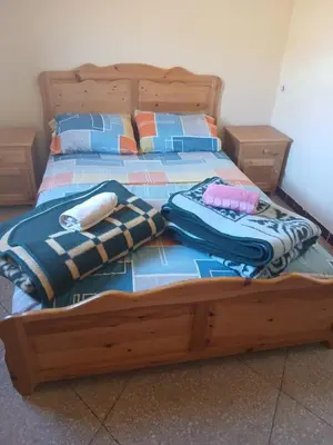 a bed with a wooden frame with clothes on it at Auberge Ighounba in Tinerhir
