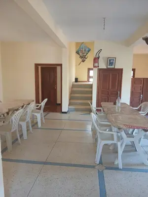 a room with tables and chairs and a staircase at Auberge Ighounba in Tinerhir