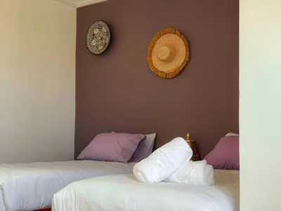 a room with two beds and a clock on the wall at Fib Houses in Ouarzazate