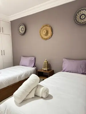 a room with two beds with white sheets and purple pillows at Fib Houses in Ouarzazate