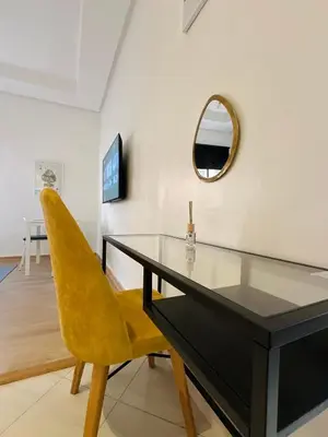 a dining room with a glass table and a yellow chair at Relax Family ApartHotel - Signature Residence in Ouarzazate