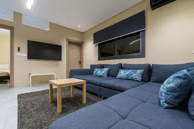 a living room with a blue couch and a tv at Relax Family ApartHotel - Signature Residence in Ouarzazate
