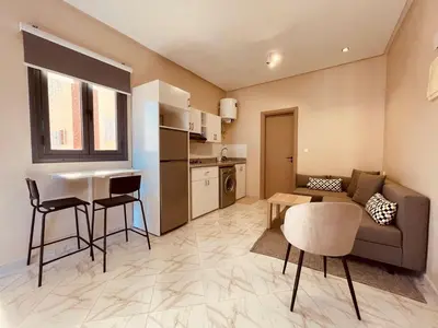 a living room with a couch and a table and a kitchen at Relax Family ApartHotel - Signature Residence in Ouarzazate
