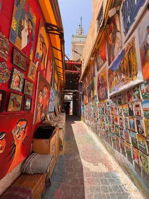 a narrow alley with a lot of pictures on the walls at Bedroom in medina in Fès