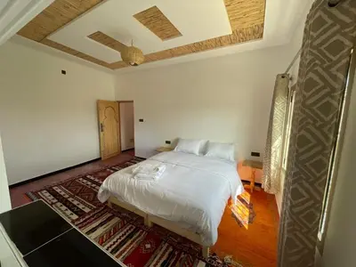a bedroom with a white bed and a rug at dar olivegarden inn in Ait Sedrate Sahl Gharbia