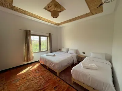 a bedroom with two beds and a window at dar olivegarden inn in Ait Sedrate Sahl Gharbia