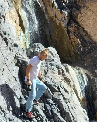a man standing on some rocks near a waterfall at Gite ditabe tafoukte