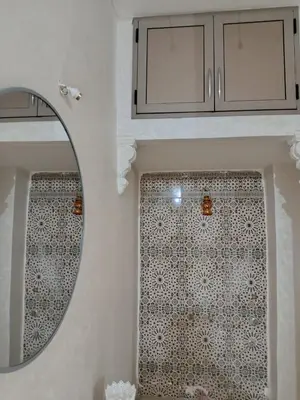 a bathroom with a mirror and a tiled wall at Dar ARAHA in Fès