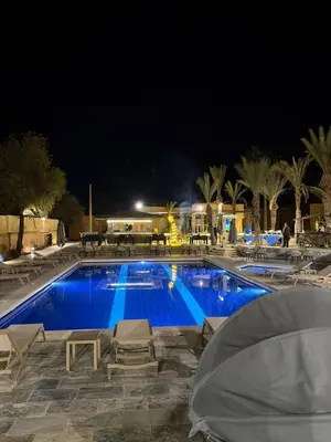 a large swimming pool with blue water at night at RS Hôtel Karam Resort in Ouarzazate