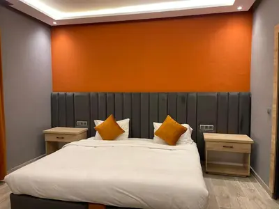 a bedroom with a large bed with an orange wall at RS Hôtel Karam Resort in Ouarzazate