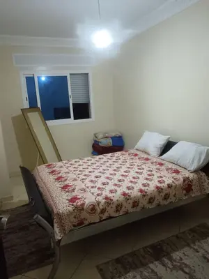 a bedroom with a bed with a red flowered blanket at Appart hôtel tanger in Oulad Akkou