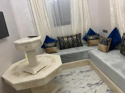 a living room with a couch and blue pillows at Al bassatine in Meknès