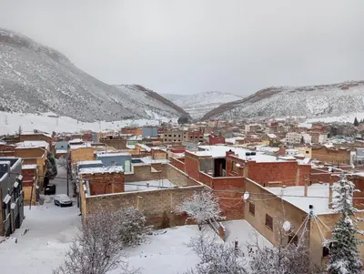 a city covered in snow with buildings and mountains at Boulemane guest house in Boulmane