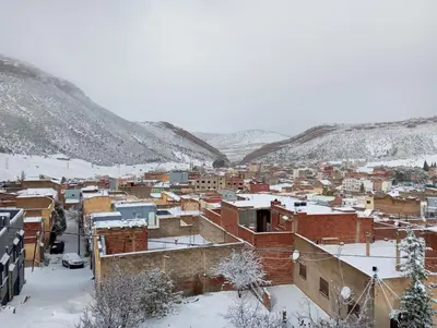 a city covered in snow with buildings and mountains at Boulemane guest house in Boulmane