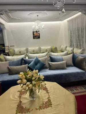 a living room with a blue couch and a vase of flowers at Appartement Jardin Prestige - Fes Centre Ville in Fès