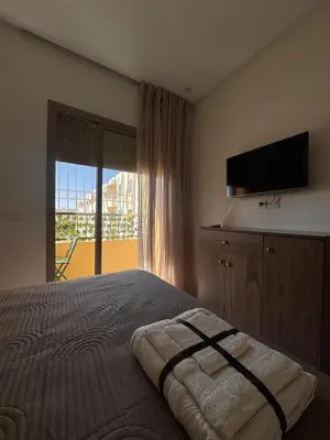 a bedroom with a bed with a television and a window at Cozy Apartment 5 min From The City Center in Fès