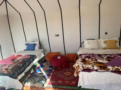 a room with two beds and a rug at farah desert camp in Kasr Bounou