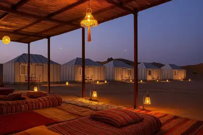 a group of lodges in the desert at night at farah desert camp in Kasr Bounou