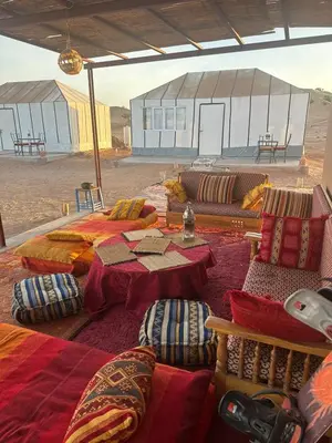 a room with beds and tables and a tent at farah desert camp in Kasr Bounou