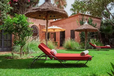 a red chair and an umbrella in a yard at Villa Boccara Marrakech in Chaibate
