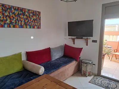 a living room with a couch and a flat screen tv at Appartement cosy avec terrasse et solarium in Oulad Akkou