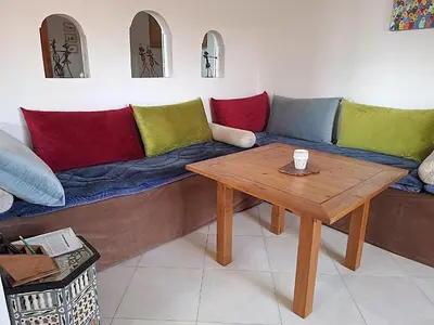 a living room with a couch and a wooden table at Appartement cosy avec terrasse et solarium in Oulad Akkou
