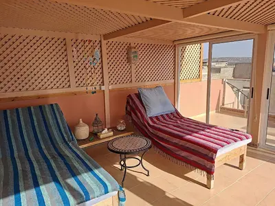 a room with a bed and a table and a window at Appartement cosy avec terrasse et solarium in Oulad Akkou