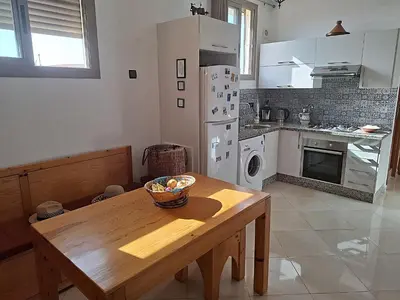 a kitchen with a wooden table and a refrigerator at Appartement cosy avec terrasse et solarium in Oulad Akkou