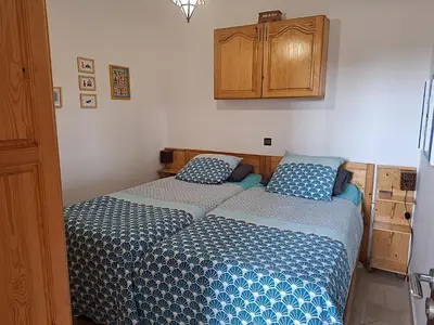 two beds in a small bedroom with blue pillows at Appartement cosy avec terrasse et solarium in Oulad Akkou
