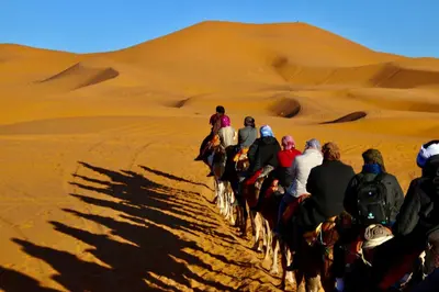 a group of people riding horses in the desert at Holiday Bivouac in Merzouga