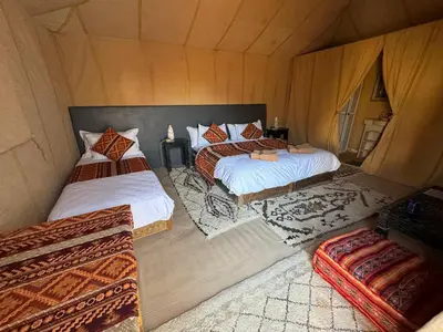 a room with two beds and two ottomans at Holiday Bivouac in Merzouga