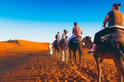 a group of people riding horses in the desert at Holiday Bivouac in Merzouga